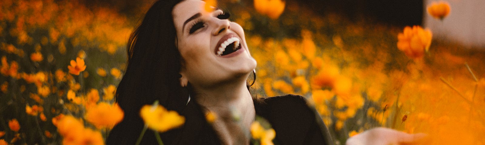 Woman laughing in a field of yellow and orange flowers