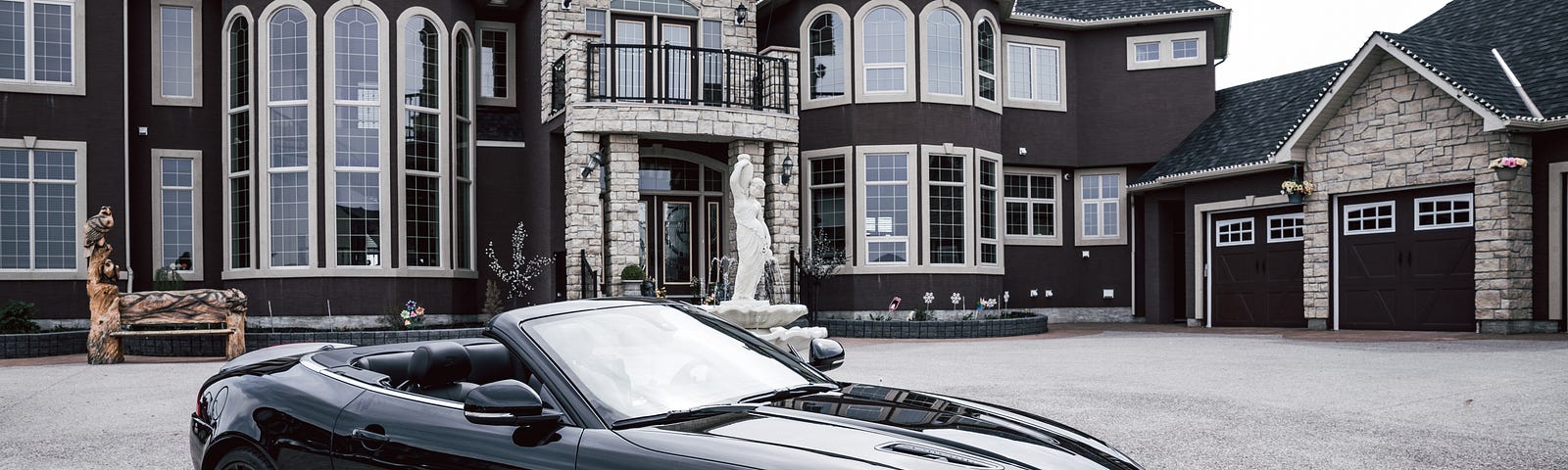 Convertible roadster in front of a mansion