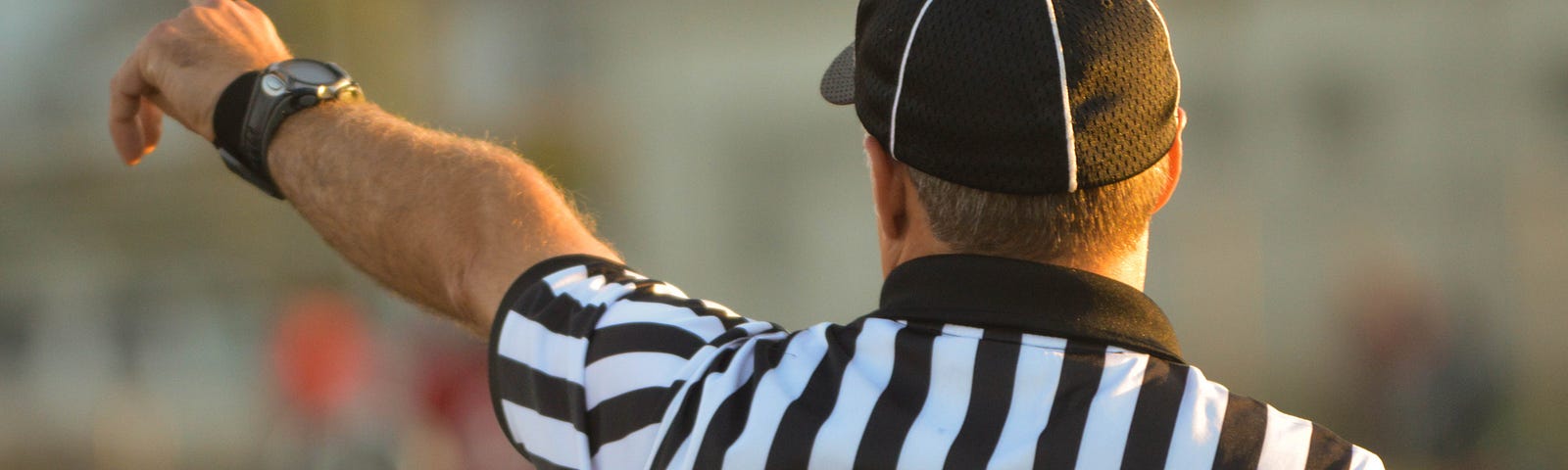 The back of a chief referee with finger pointing out into the distance as if calling the play.
