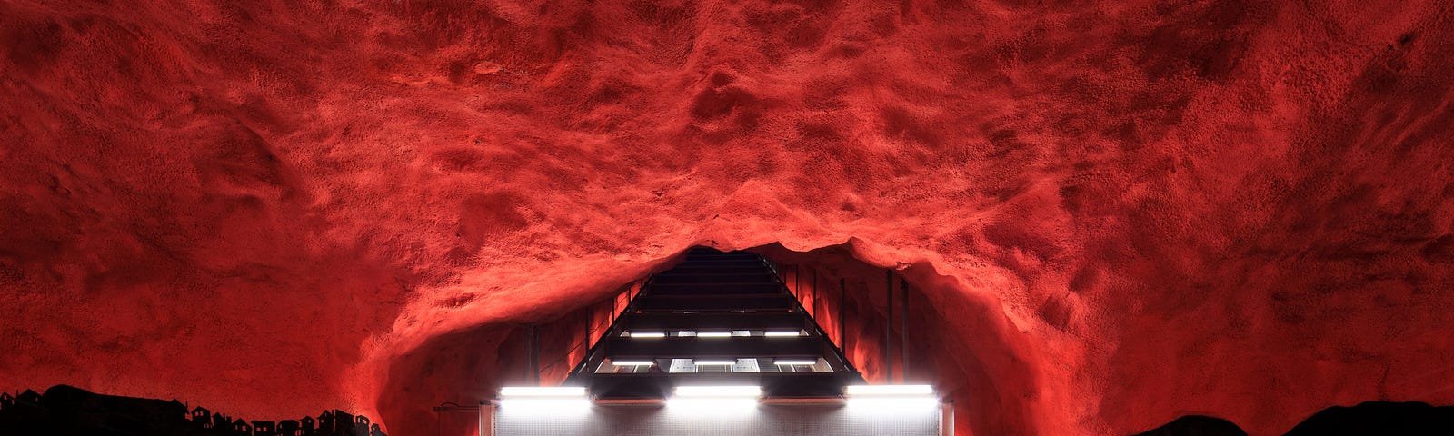 4 sets of escalators in a darkened tunnel leading up out of the transit hub surrounded by figurative red clouds swallowing the periphery of it all. A metaphysical way of viewing whether NFTs are right for you.