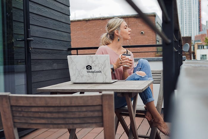 A woman sitting at a laptop drinking coffee.