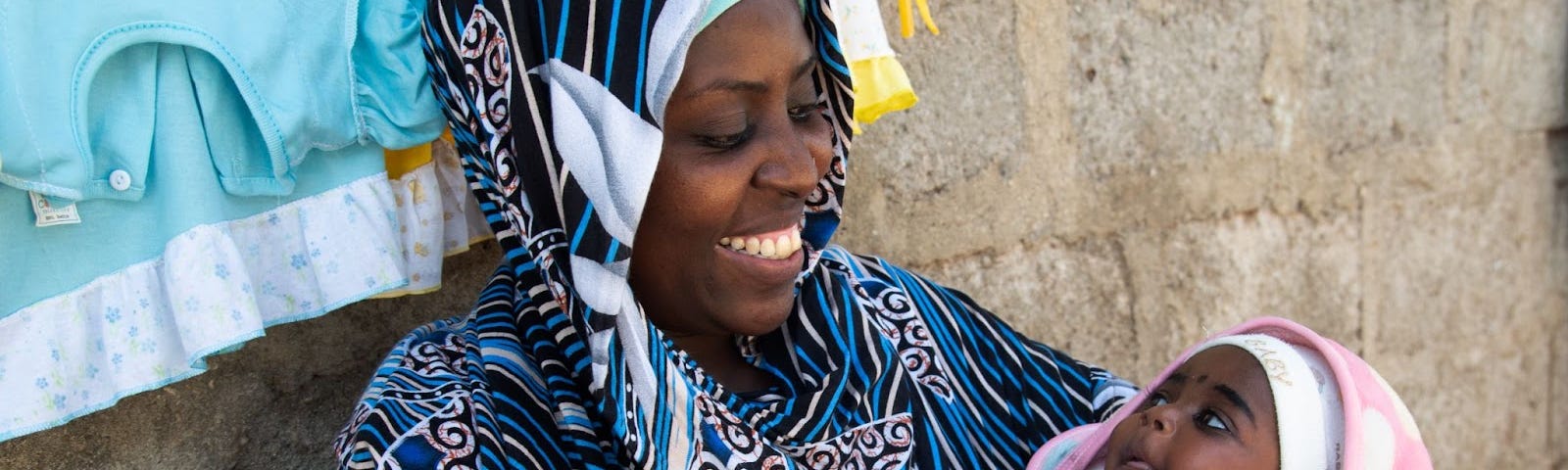 Miza Juma Juma, a new mom in Tanzania, smiles lovingly at her newborn baby, Umulayman, who she is cradling in her arms.
