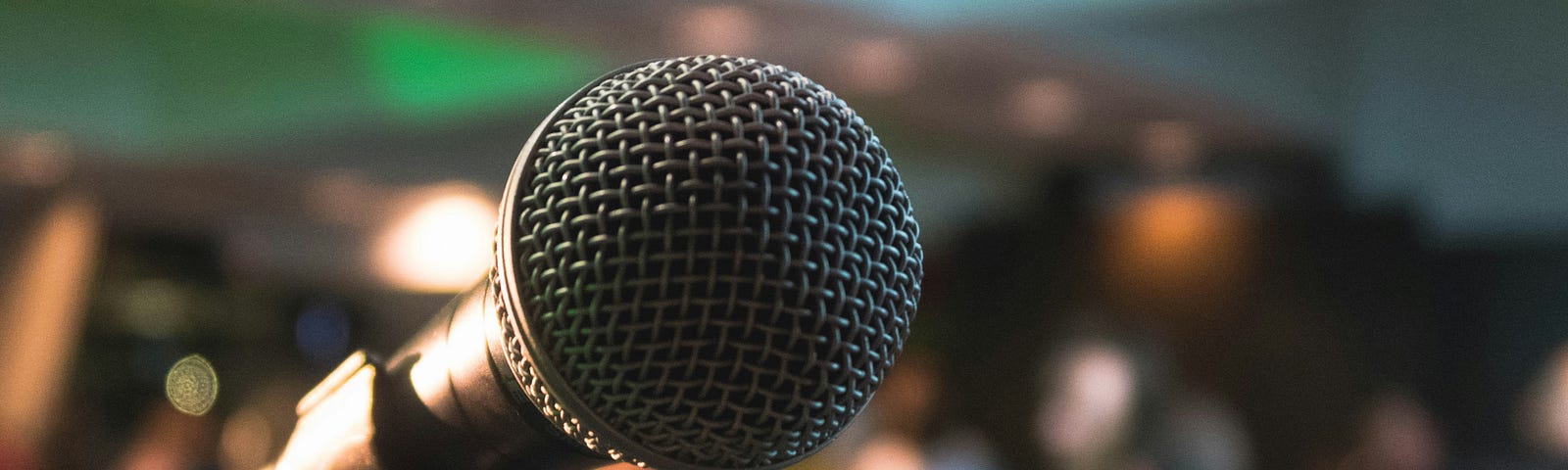 A microphone standing in front of an audience ready to hear you speak