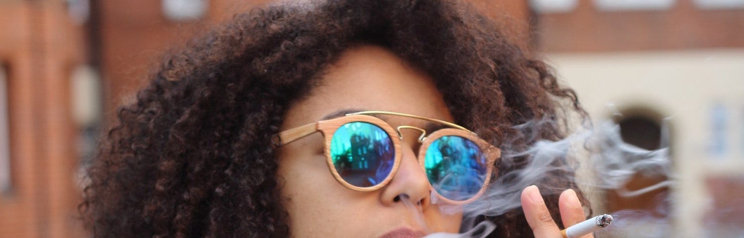 A black girl wearing sunglasses smoking a cigarette for the story That’s It! I Quit! by Jonica Bradley