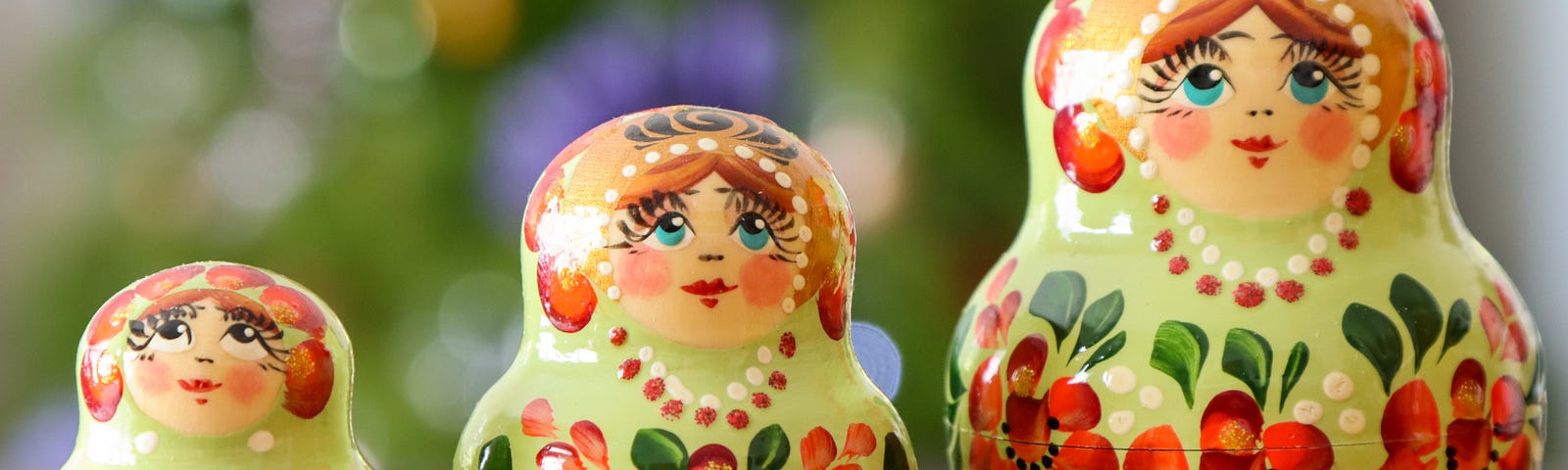 3 colorful Russian nesting dolls, depicting a young child, a middle child, and a mother