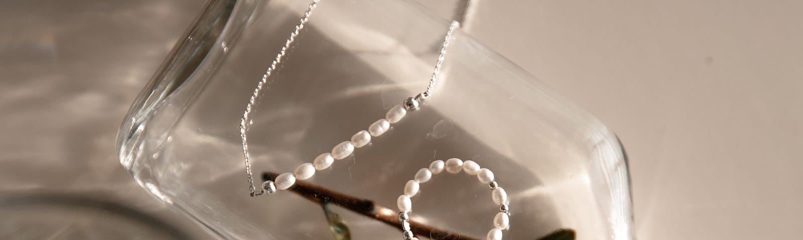 pearls laid out on a bottle with greenry on its side