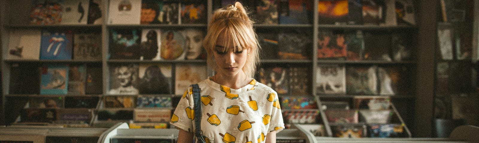 A young woman in a colourful T-shirt browses records in a vinyl record store