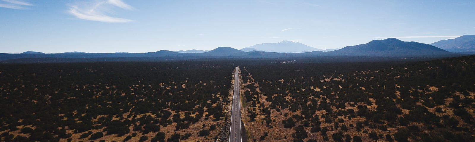 Aerial photo of a long stretch of highway traveling off into the mountains.