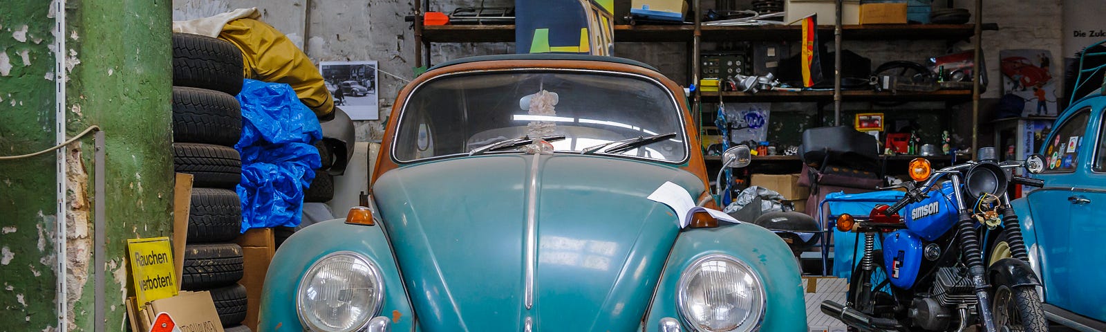 An antique car in a garage packed full of stuff. Swedish death cleaning