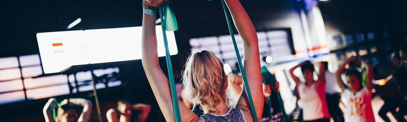 A group of women perform exercises with resistance bands in a fitness studio.