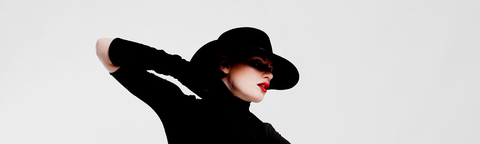 Dramatic image of woman in black top, gloves and hat, red lipstick