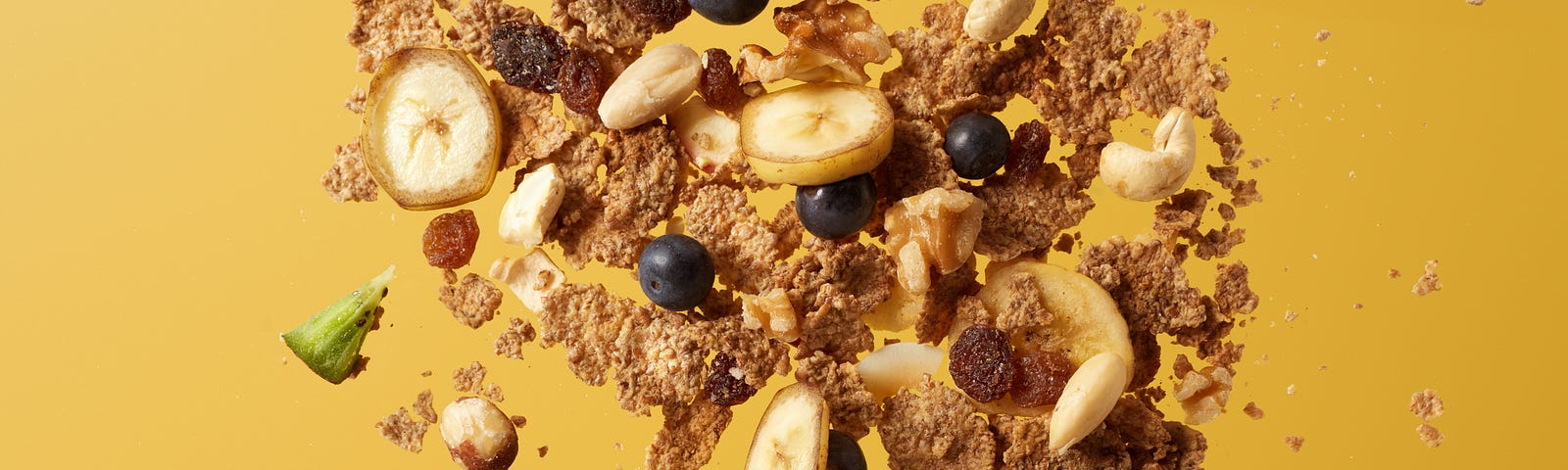 Cereal and fruits appear to spill upward from a small white bowl. ustard colored background. Calorie restriction alters methylation and causes changes that suggest slower aging.