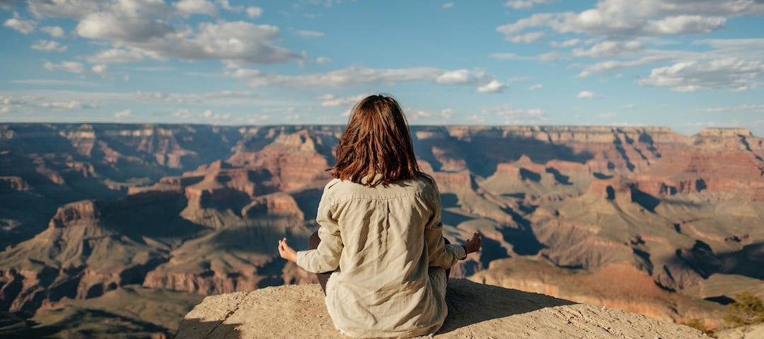 A woman meditates on a mountain.