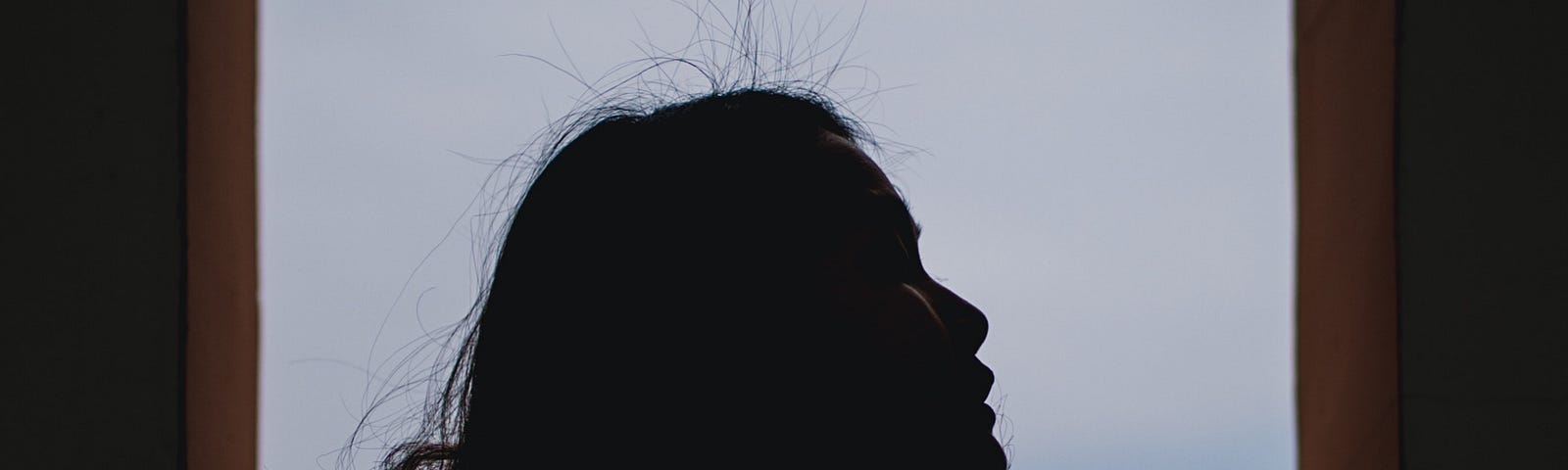 Silhouette of a girl in front of a door, looking up