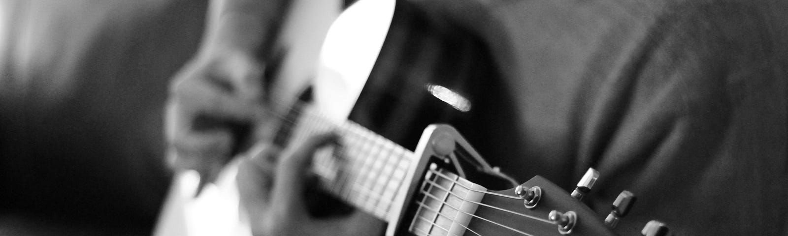 close up of young bearded male playing guitar