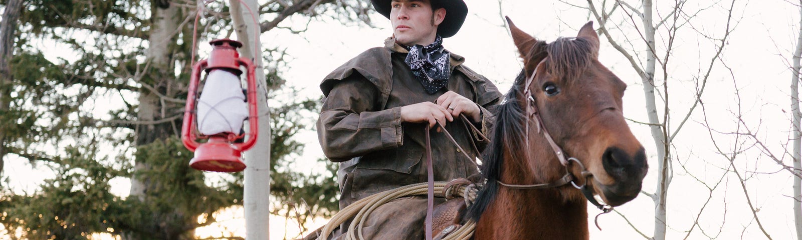 cowboy wearing leather rain gear riding a chestnut horse