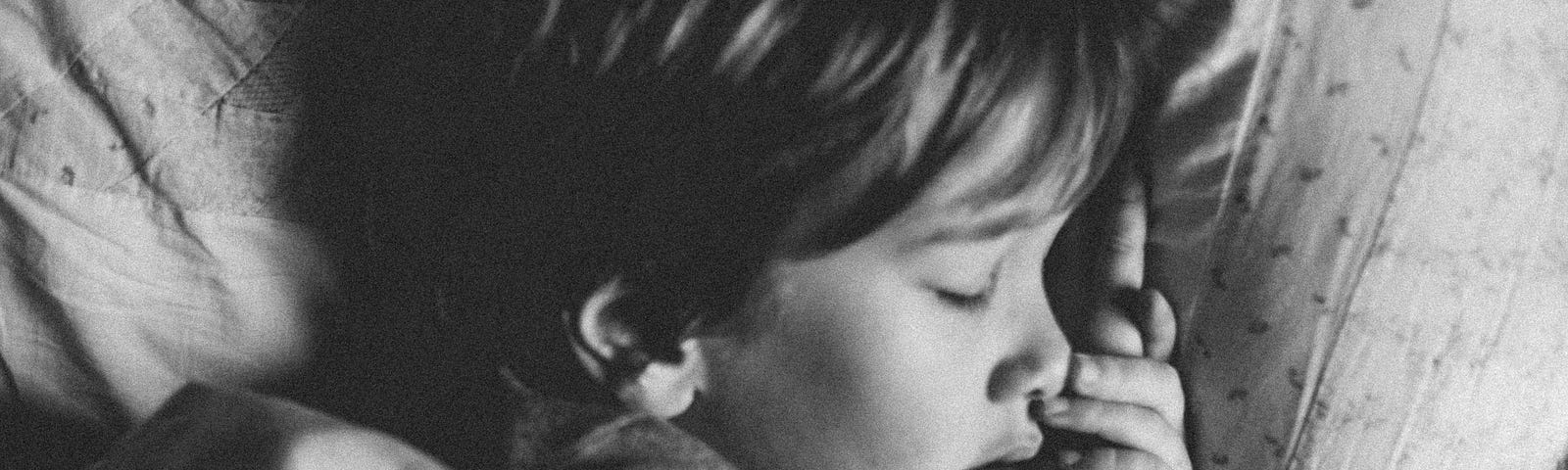 Black and white of boy sleeping on pillow.