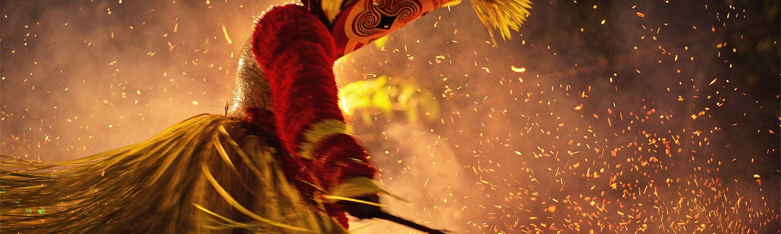 Indian fire dancer costumed in red with mask and swirling sparks.