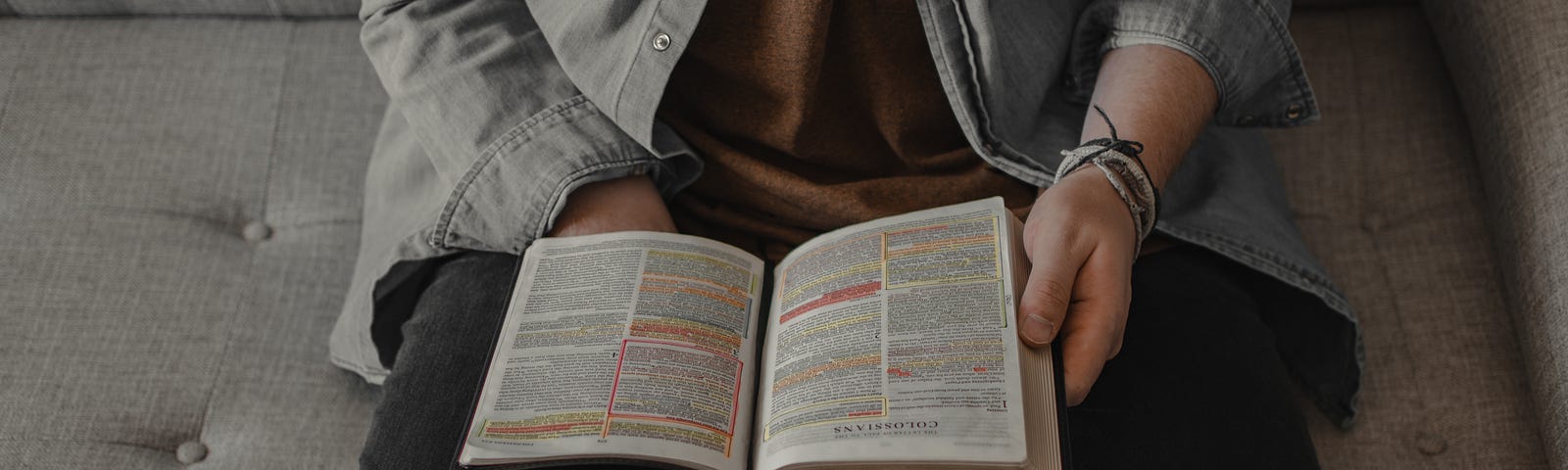 Man sitting on a sofa with a Bible open on his lap