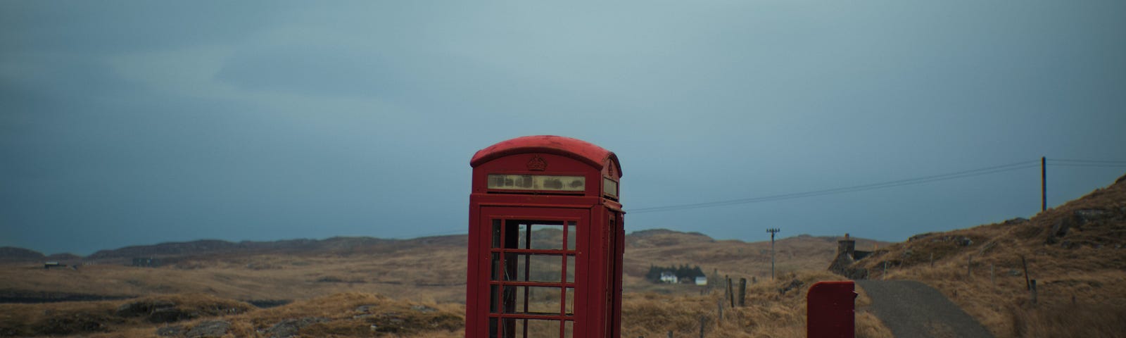 An abandoned red British phone booth in a barren landscape