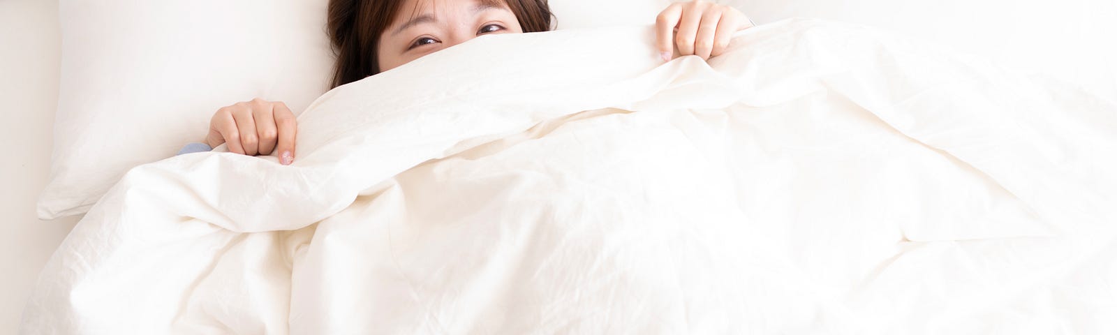 picture of a woman snuggled under the covers in bed