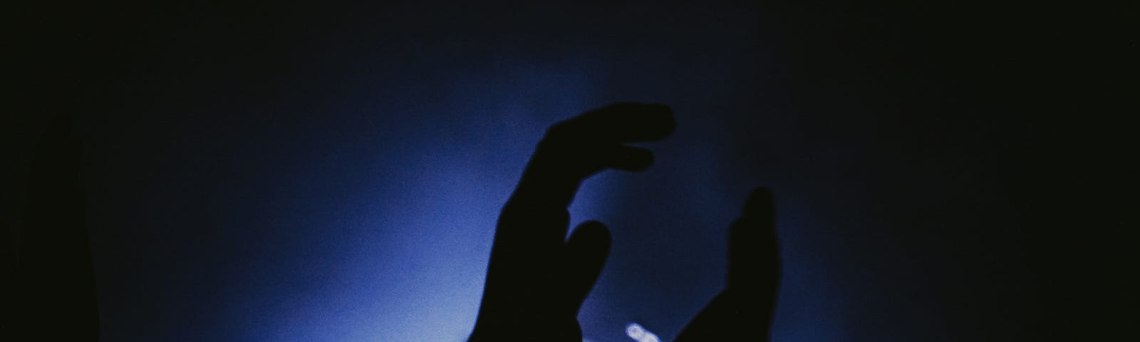 A dark room with a close up of a pair of hands clapping.