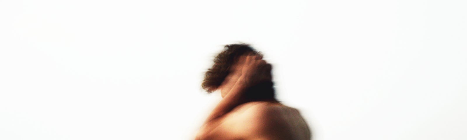 Blurred photo of shirtless man covering his ears