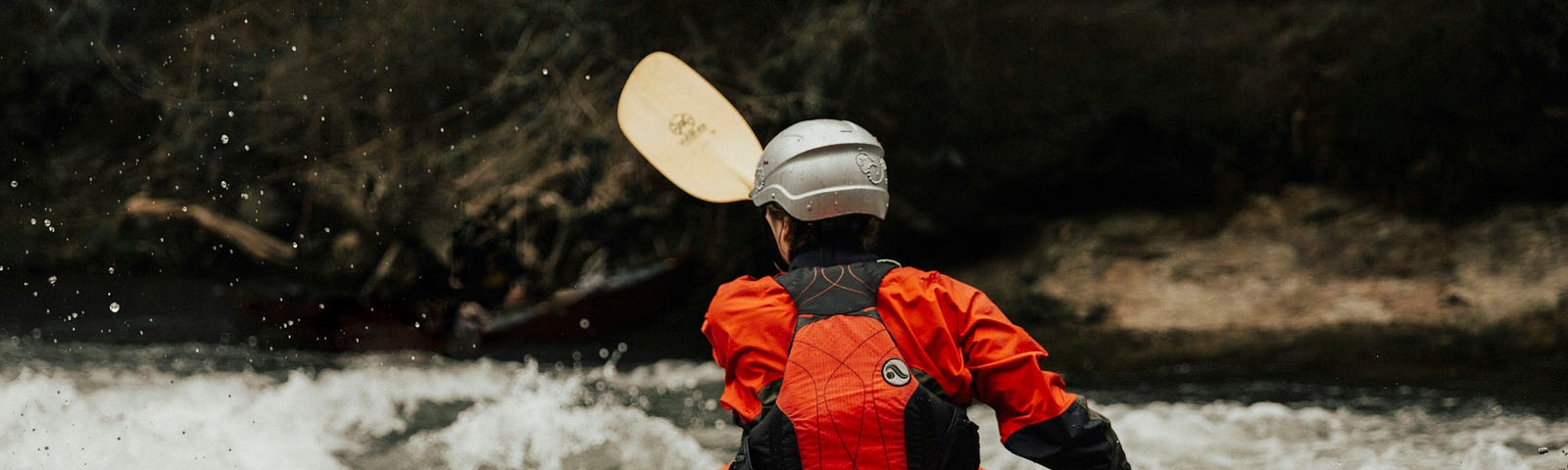 A kayaker wearing a helmet heading into white water.