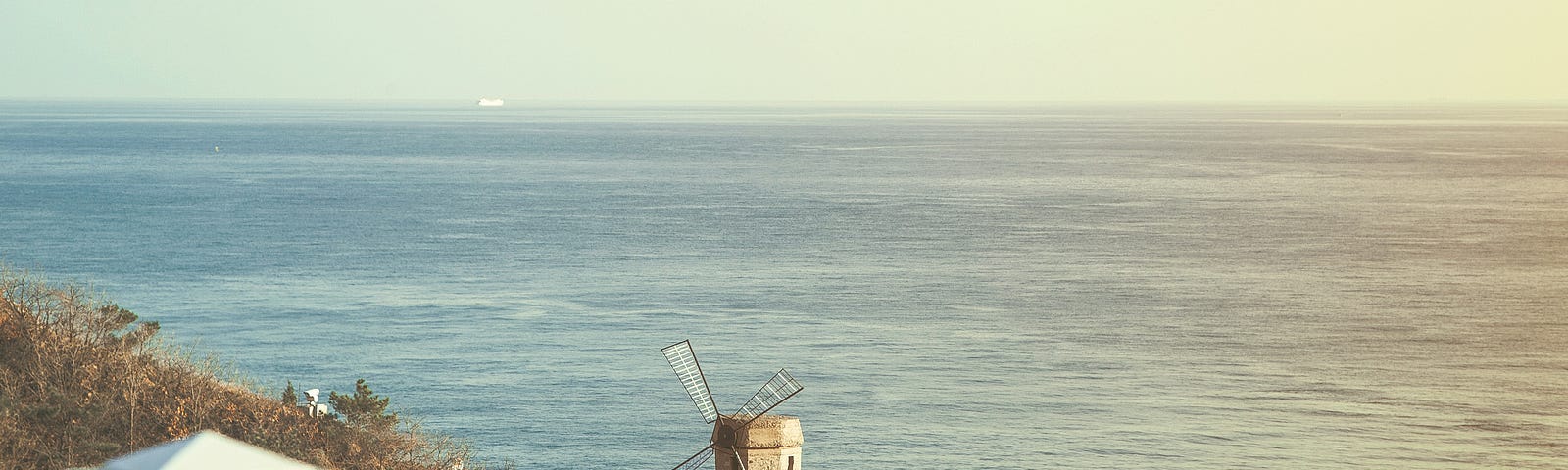 A windmill by the sea on a sunny day