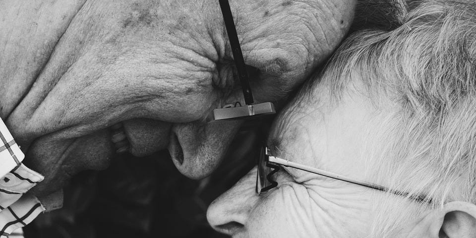 An elderly couple embraces
