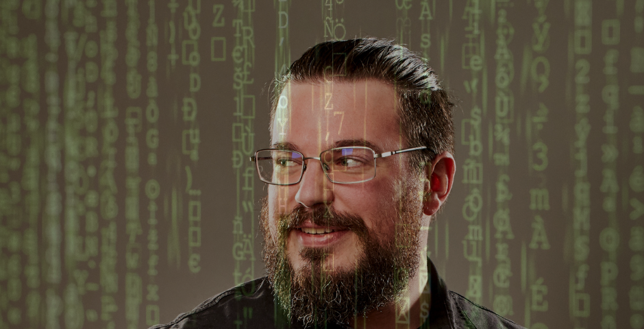 A portrait of a man (Justin) glancing over his shoulder. The Matrix-style green code is falling all around him.