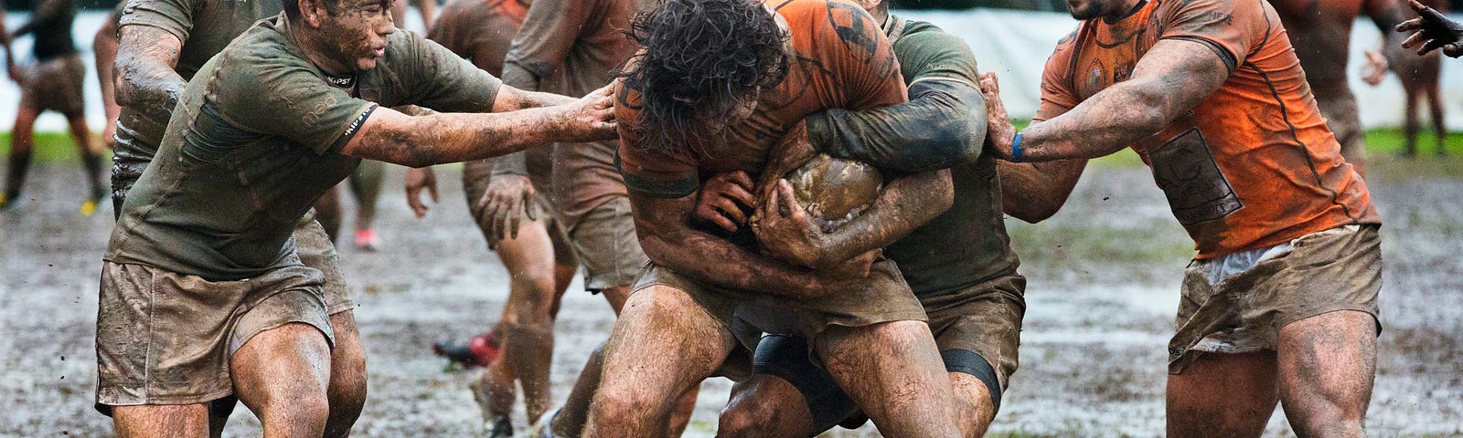 Guys playing rugby in the mud