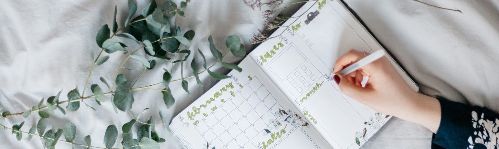 Woman writing in bullet journal surrounded by leaves