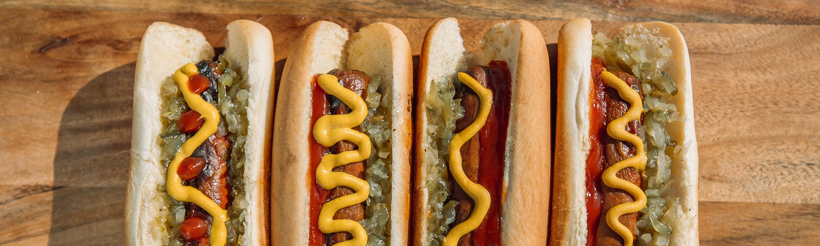 four hot dogs in a row with mustard relish and ketchup