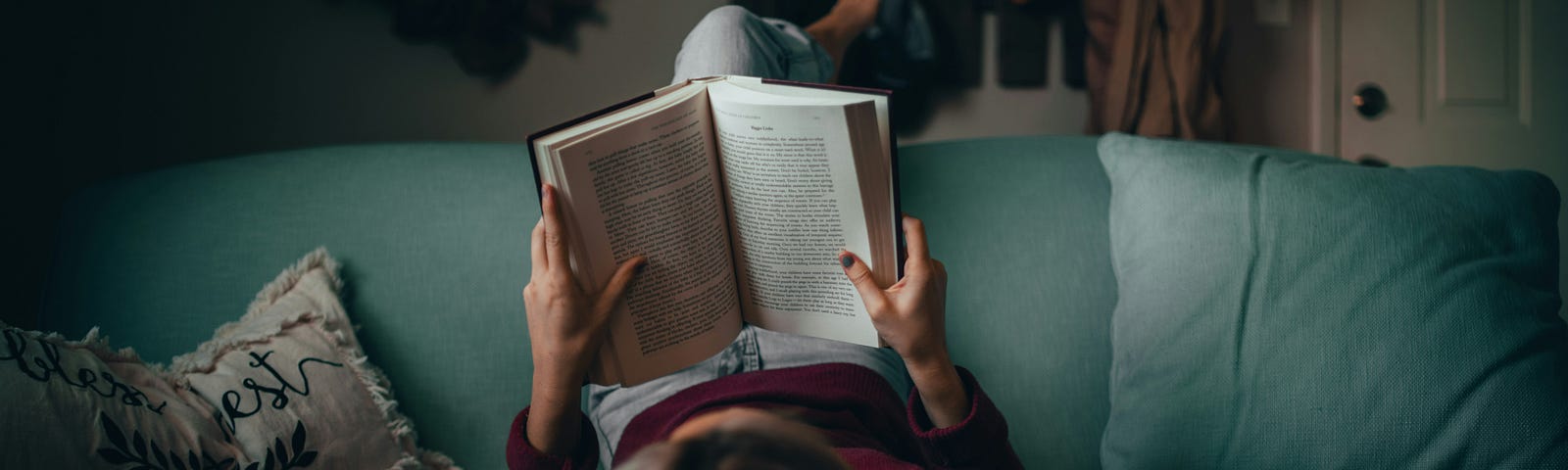 woman on a couch reading a book upside down