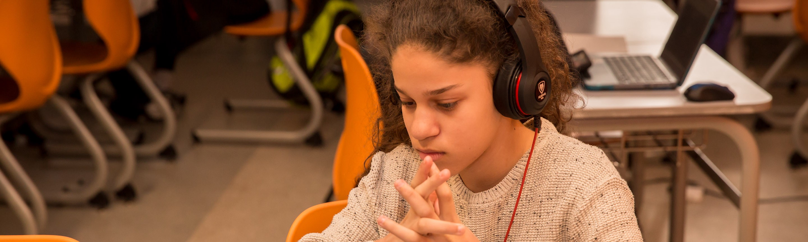 A student wearing headphones completes a CommonLit assignment on a laptop.