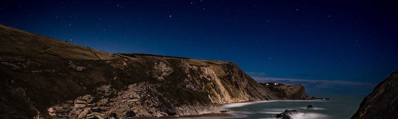 Sea cliffs around a bay at night