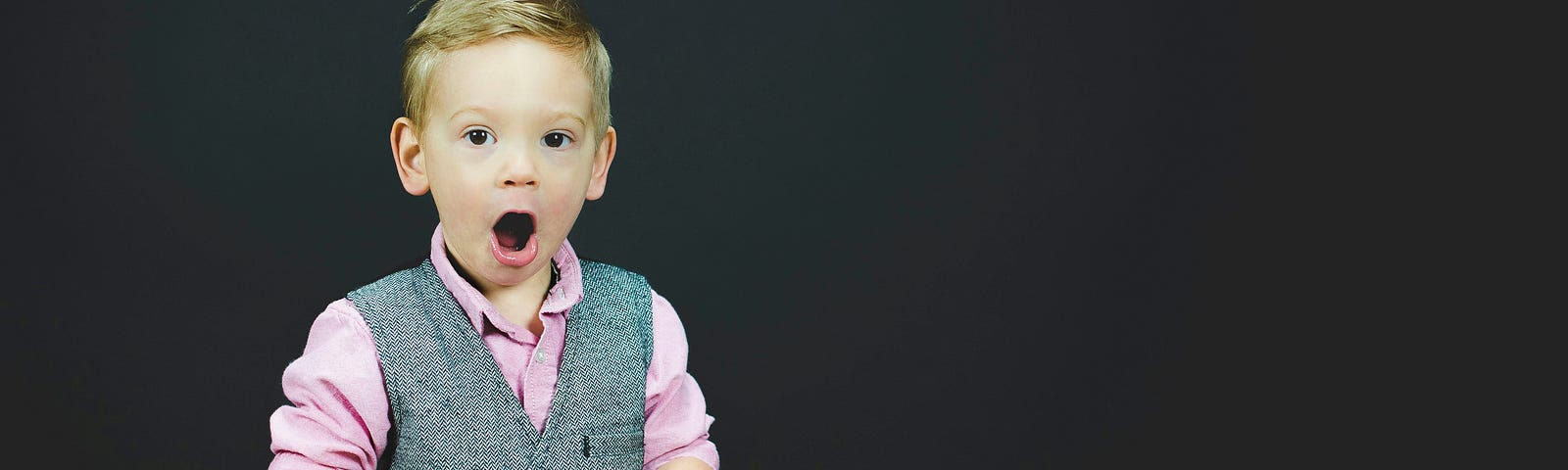 Boy with book, and a surprised expression on his face.