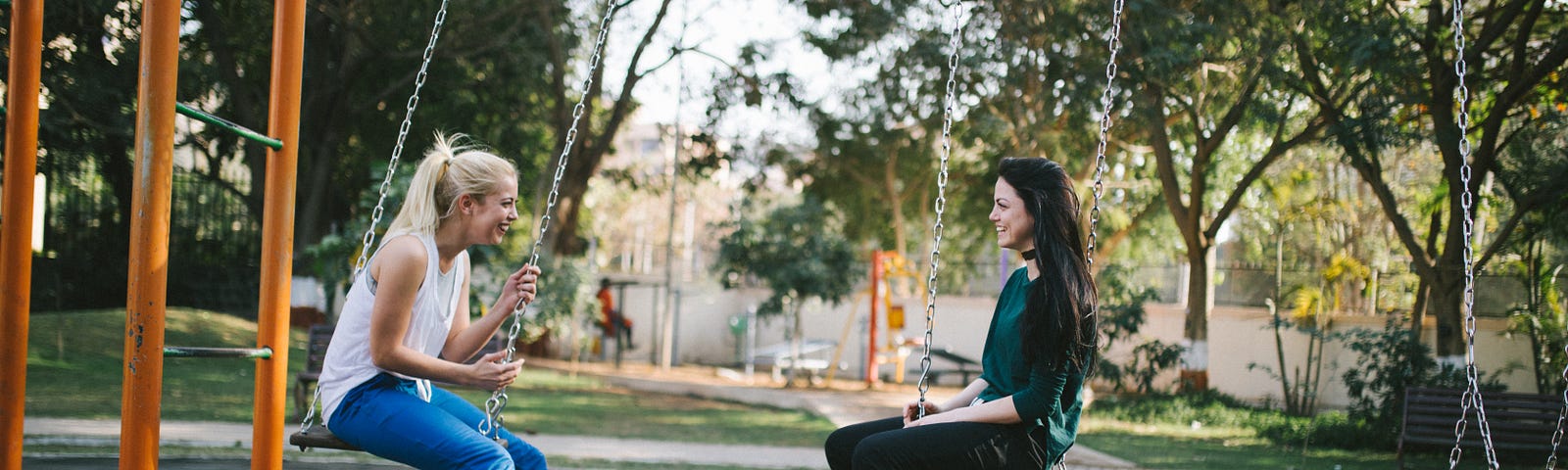 Two women sitting on swings having a conversation