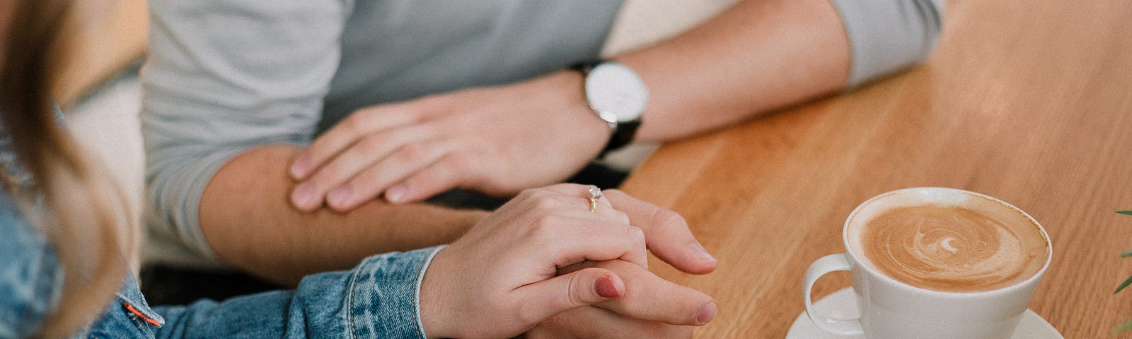 A couple holding hands while they sit and have a coffee