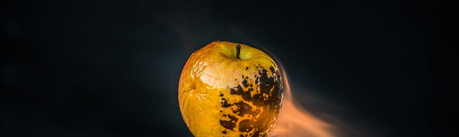An apple having heat from a blowtorch applied to it.