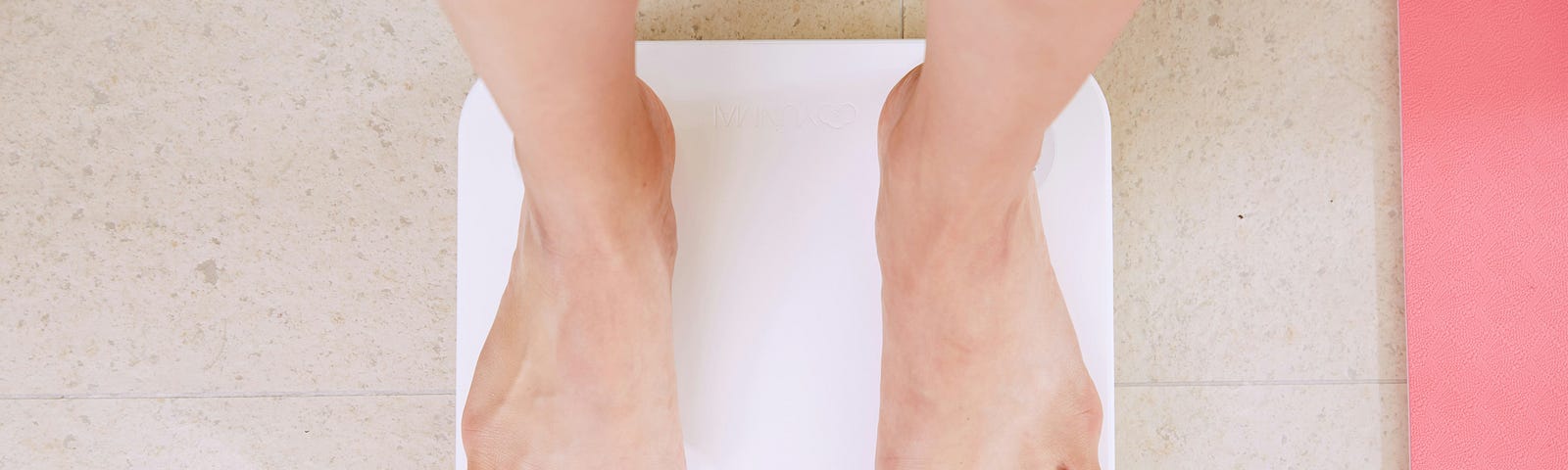 Feet standing on bathroom scales.