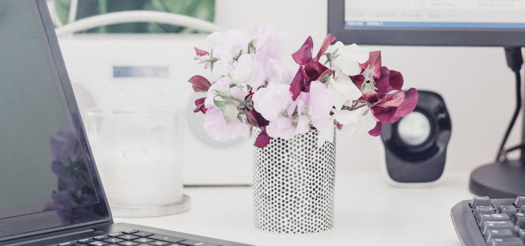 Vase of flowers on desk near laptop