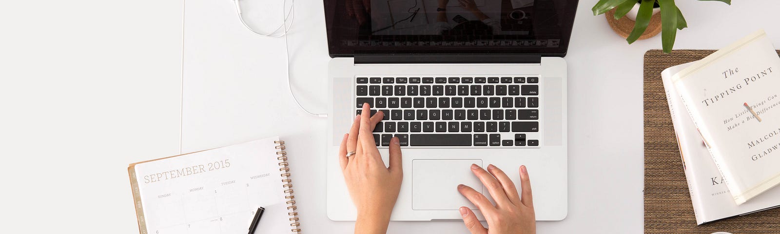 A lady sitting at a laptop with a daily planner open and coffee by her side.