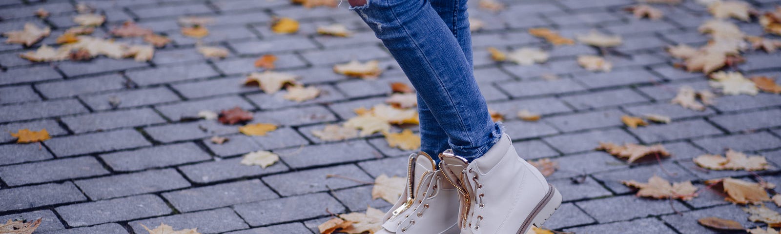 A woman wearing ripped jeans and white sneakers