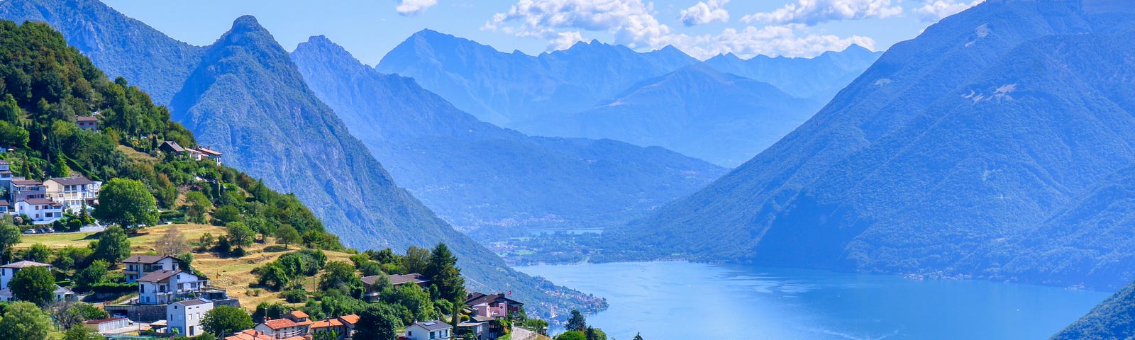 A view of a Swiss village on Lake Lugano with mountains in the background, the setting for this story