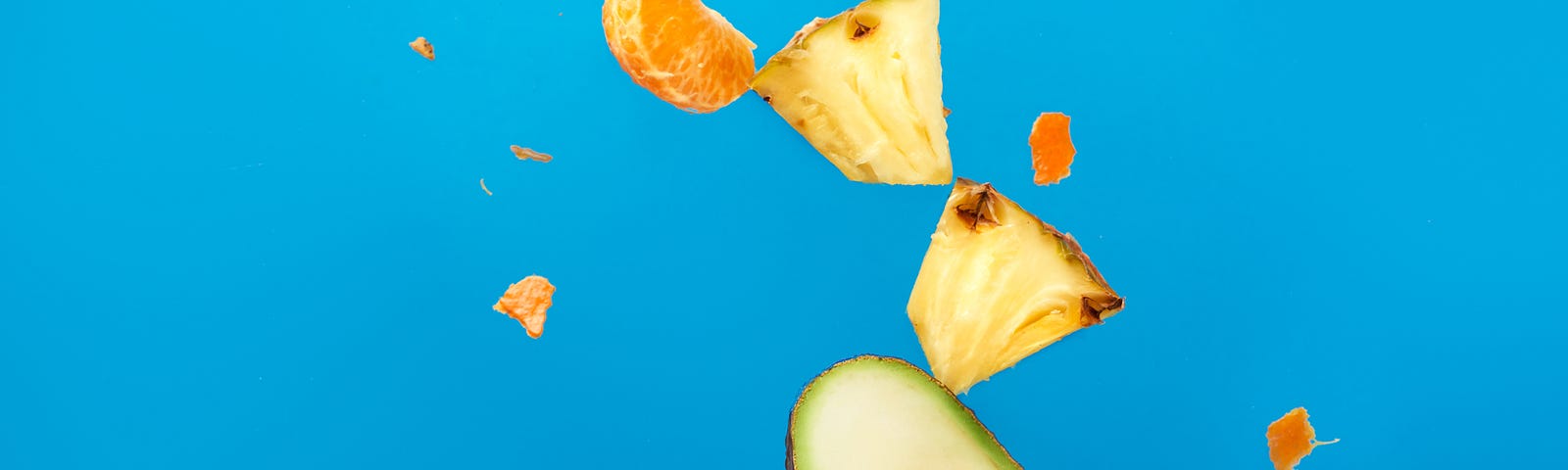 Avocado piece and other fruits rise up off of a fork, flying through the air against a light blue background.