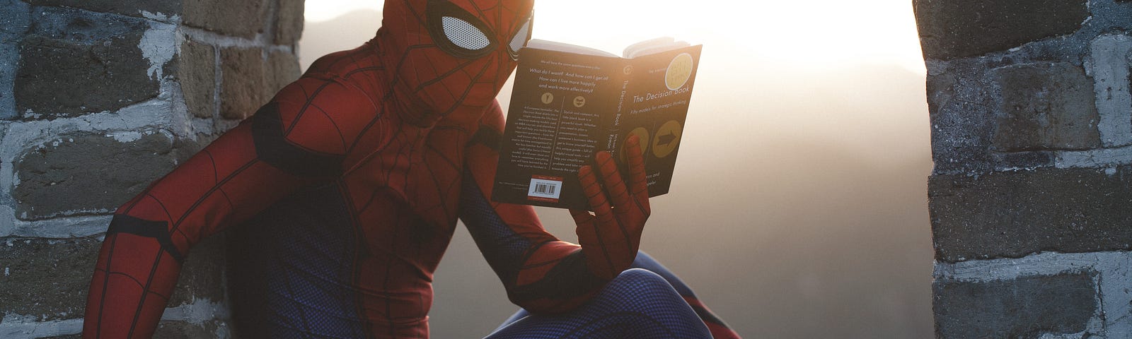 Spiderman sitting and reading a book.