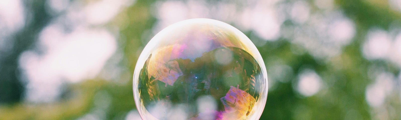 A single soap bubble floating in front of a blurred green background.