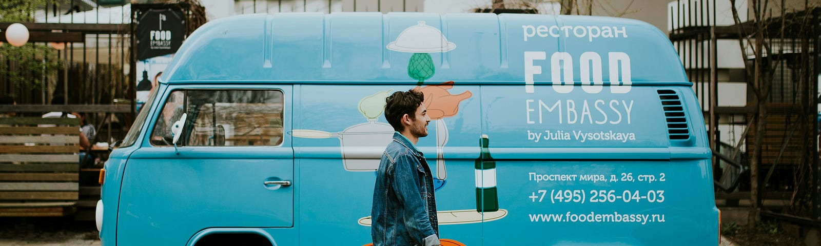 A hipster young man walking around the streets was photographed in front of a blue hippie van